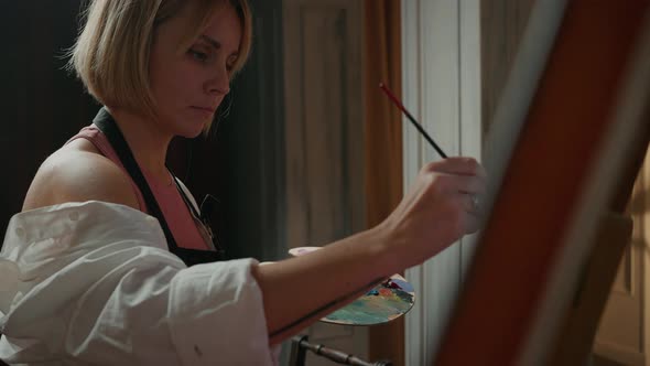 Close Up Portrait of Young Concentrated Woman Artist in Apron Painting Picture at Studio Using alt