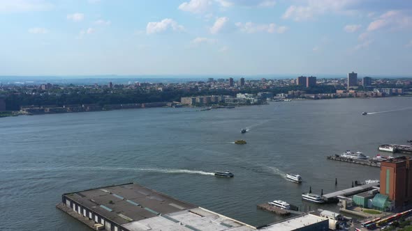 Aerial footage of several ferry boats docking at a pier on the Hudson River, viewed from the New Yor alt