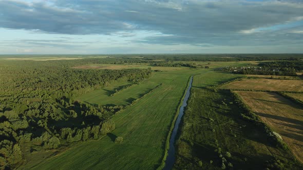Flight Over The River In The Valley. A Village In The Middle Of The Forest Is Visible In The Distanc alt