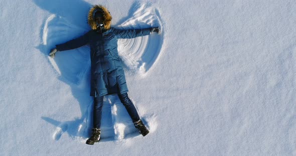 Woman Makes Snow Angel Laying in the Snow