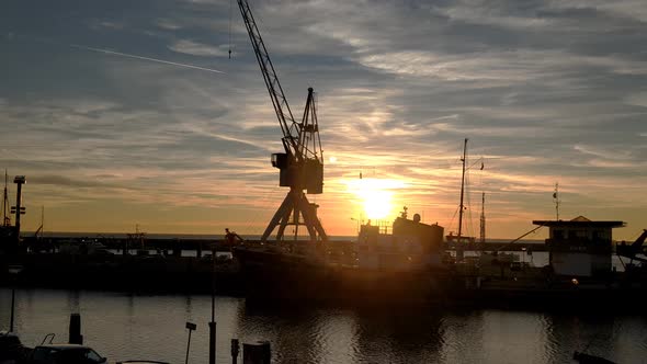 Dolly shot of a sun set in the harbour of Harlingen. Tug boat Holland and a vintage crane, backlight alt