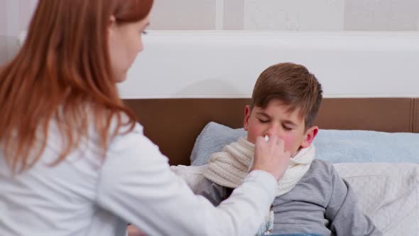 Mother Takes Care of Her Son's Health and Drips Nose Drops From a Cold alt