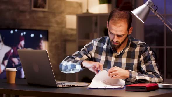 Businessman Typing on Laptop and Searching Through Documents alt