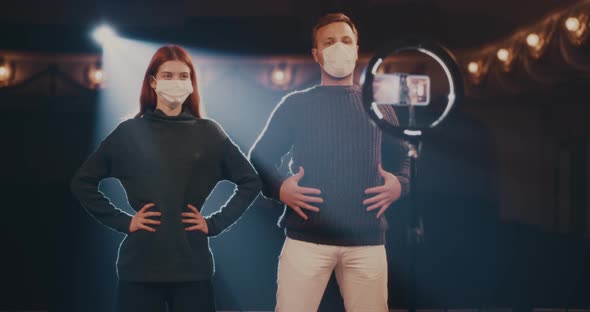 Actor and Actress in Masks Showing Breathing Exercise for Online Audience alt