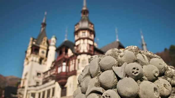 View of a sculpture at The Peles Castle in Romania. Castle on the background, tourists alt