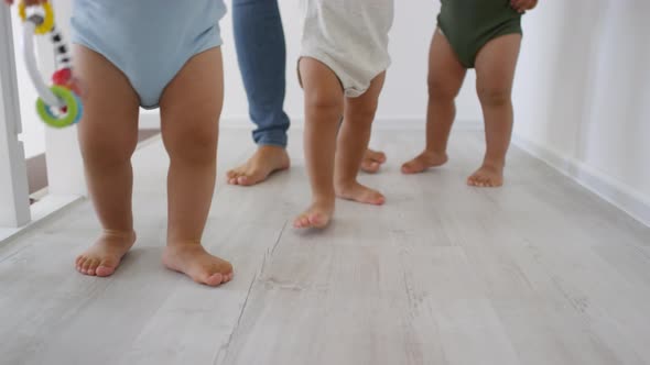Legs of Triplet Toddlers Walking Together at Home alt