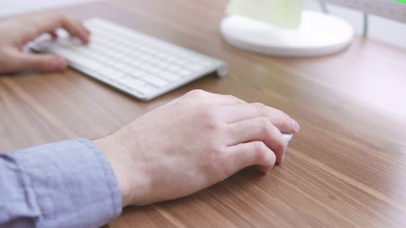 Top View of a Young Man's Hands Working with Computer Keyboard and Mouse alt