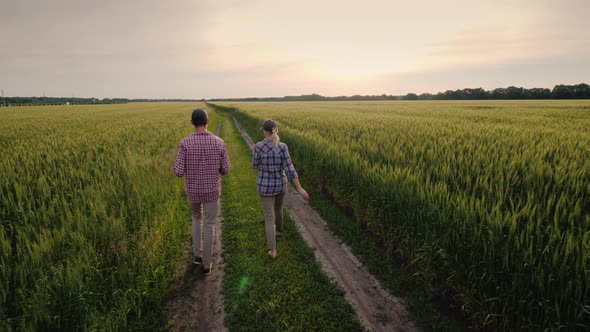 Farmers Walk Along Country Road Along Green Wheat Fields alt