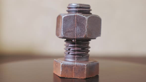 A Bolt with a Nut Rotates Closeup on a Light Background alt