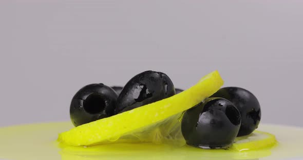 Black Olives with Lemon Spinning in a Frame on a White Background alt