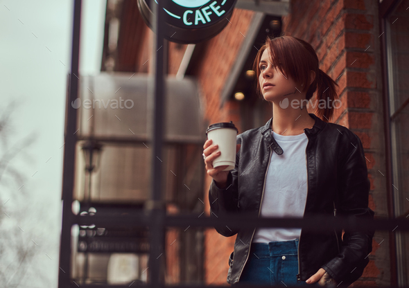 Coffee on the go. Stylish and young woman in coat and hat drinking