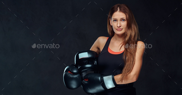Beautiful brunette female boxer in sportswear. Isolated on dark textured background.