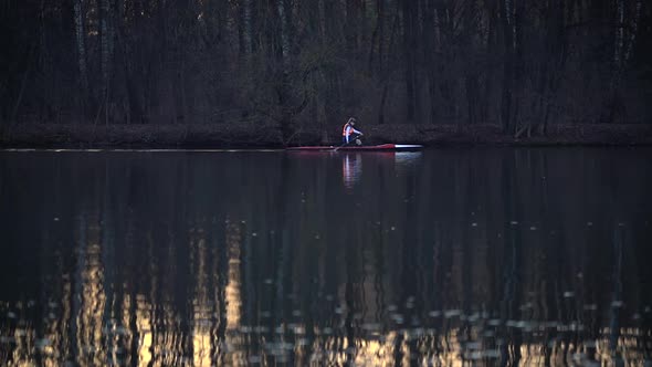 Woman Is Kayaking Alone in River at Sunset on Forest Background in Slow Motion
