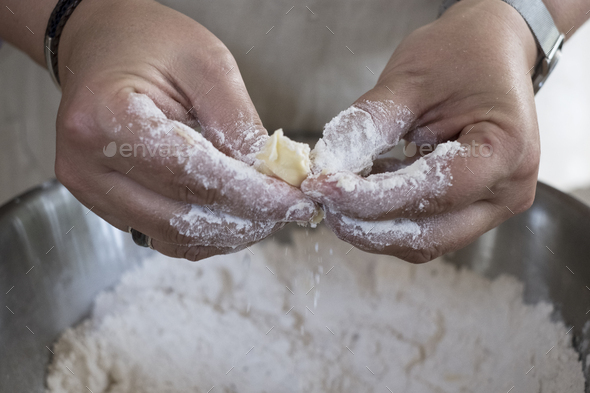 Close up of person rubbing in butter and flour for a crumble between her finger tips.