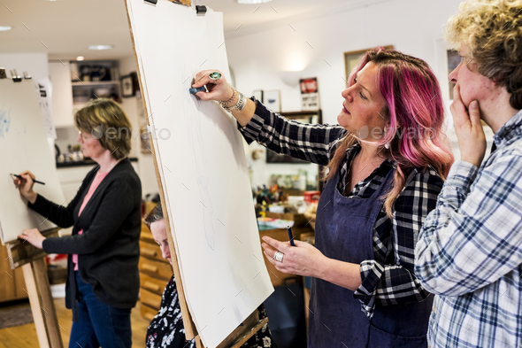 Woman standing at an easel, drawing a human leg at a life drawing glass.
