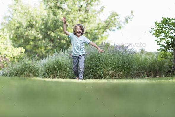 5 Year Old Boy Running On Green Lawn Stock Photo By Mint_Images | PhotoDune