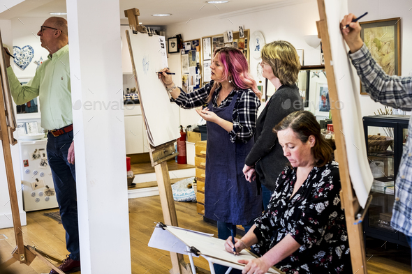Group of artists standing and sitting at easels, drawing.