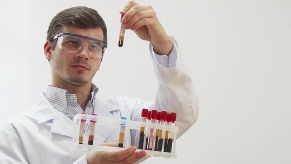 The Doctor Wearing Special Laboratory Glasses Examines Test Tubes with Blood alt