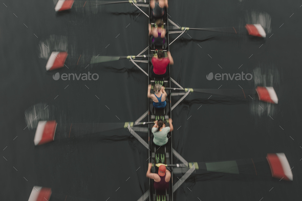 Blurred motion overhead view of a rowing crew in a sculling boat on the water, mid stroke