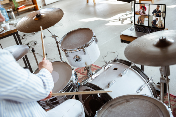 Close up of caucasian musician playing drumms during online concert with the band at home isolated