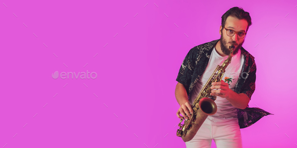 Young caucasian jazz musician playing the saxophone in neon light, flyer with copyspace for ad