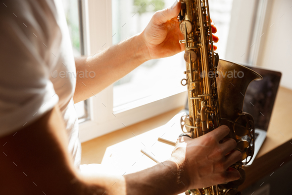 Caucasian musician playing saxophone during concert at home isolated and quarantined, impressive