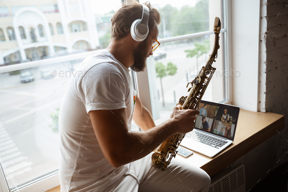 Caucasian musician playing saxophone during online concert at home isolated and quarantined