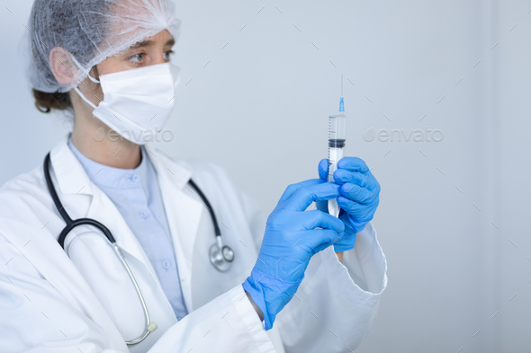 Healthcare worker holding a vaccine and wearing coronavirus Covid19 mask