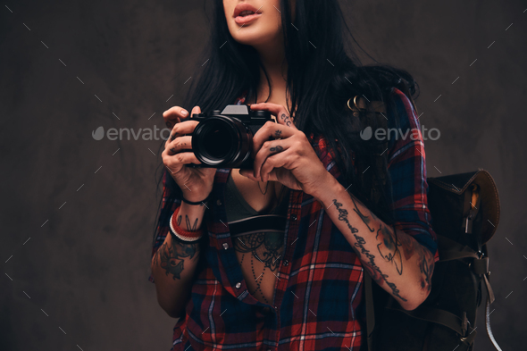 Sexy tattooed hipster girl wearing a red unbuttoned checkered shirt and shorts