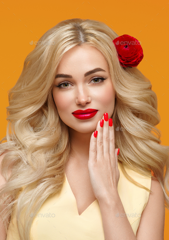 Beauty woman long curly blonde hair flower in hair manicured nails. Trendy colors orange and yellow