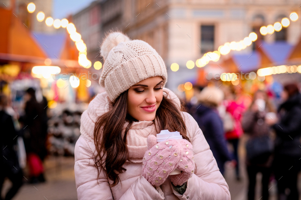Beautiful girl in winter clothes standing on the street with a fair during Christmas time