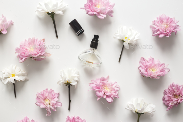 Flat lay composition with spring flowers and perfume jar on white background. Top view, flat lay