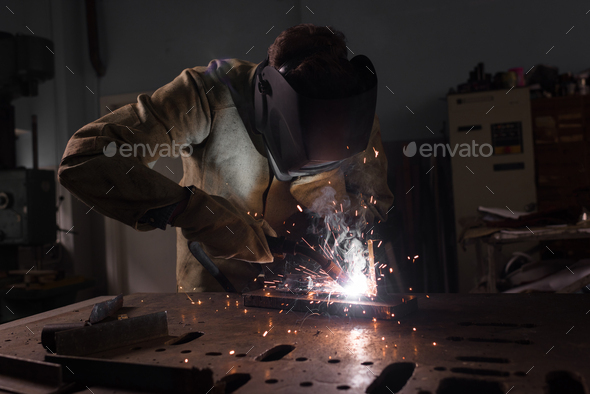 Worker in Protection Mask Welding Metal at Factory
