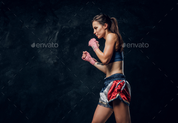 Portrait of nice female boxer at dark photo studio