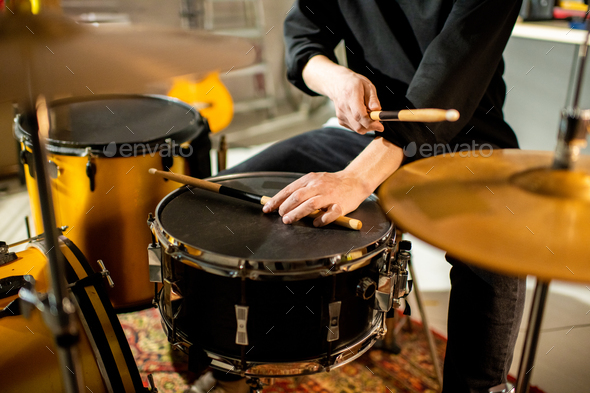 Hand of young musician putting drumstick on black drum during rehearsal
