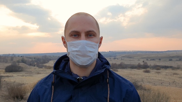 Caucasian young man with medical protective face mask looking alt