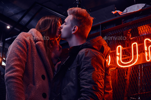 Young stylish couple wearing warm clothes standing on the staircase to the underground nightclub