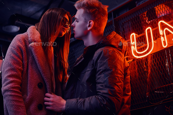 Young stylish couple wearing warm clothes standing on the staircase to the underground nightclub