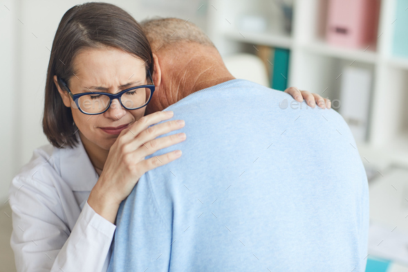 Female Doctor Embracing Crying Senior Man