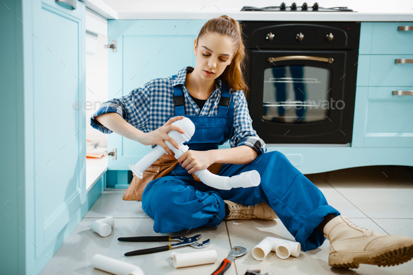 Female plumber fixing problem with drain pipe - Stock Photo - Images