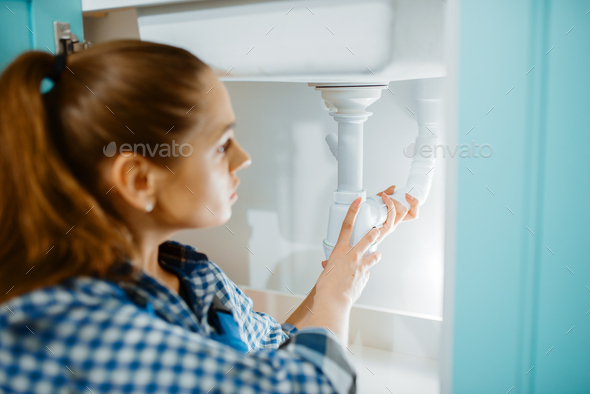 Female plumber in uniform installing drain pipe - Stock Photo - Images