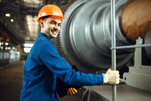 Engineer on factory, large turbine on background