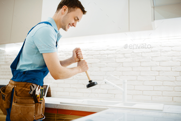 Male plumber in uniform holds plunger, clog - Stock Photo - Images