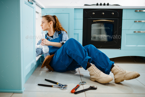 Cute female plumber in uniform holds drain pipe - Stock Photo - Images