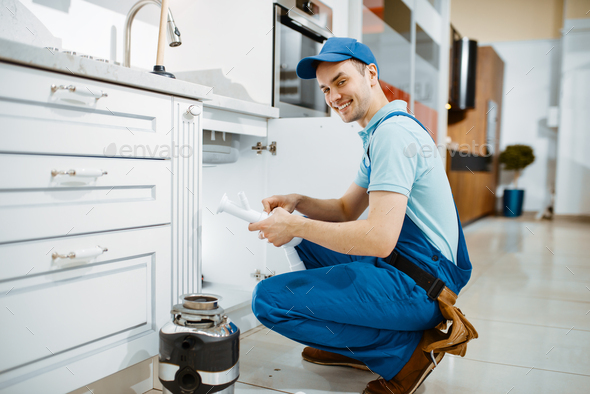 Smiling male plumber in uniform holds drain pipe - Stock Photo - Images
