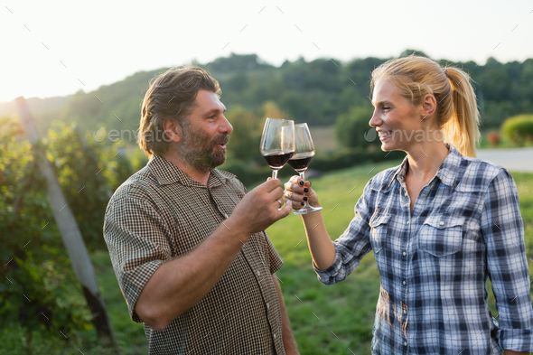 Wine growers toasting with red wine in vineyard