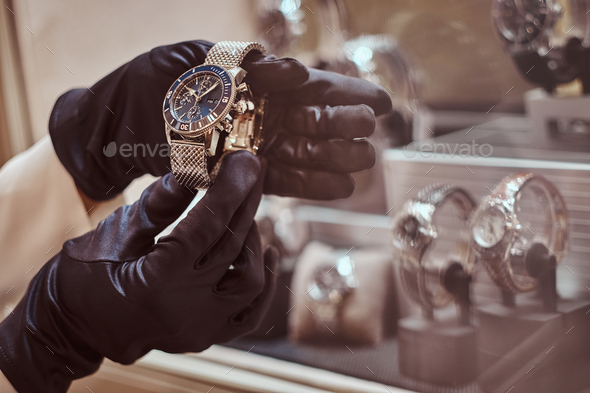 Close-up of the seller\'s hands in gloves shows the exclusive men\'s watch from the new collection