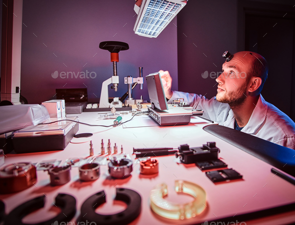 Focused watchmaker is working at his own studio.