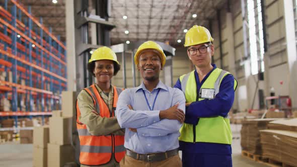 Portrait of diverse workers wearing safety suits and smiling in warehouse alt