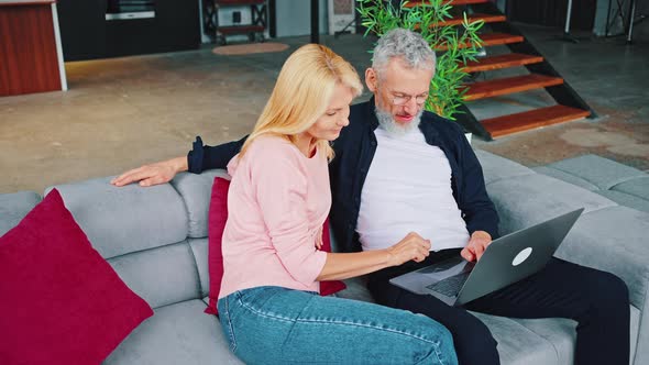 Married Couple Doing Internet Shopping While Sitting on the Couch alt